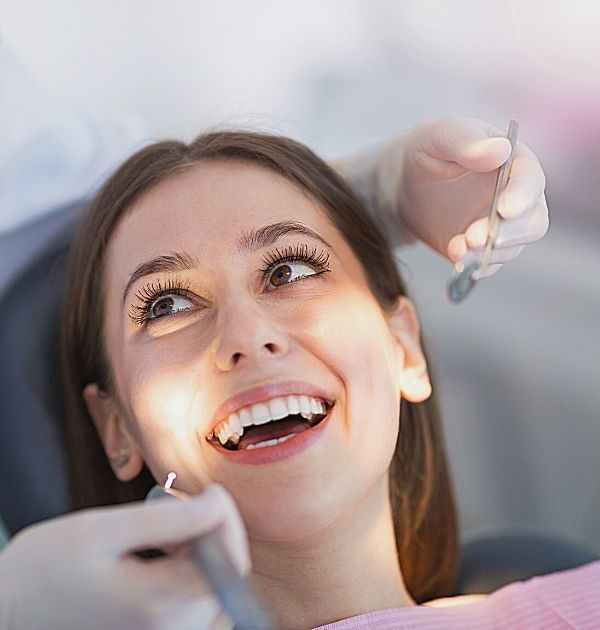 Frau lächelt bei einer zahnmedizinischen Untersuchung