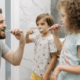 Vater und zwei Kinder putzen sich die Zähne